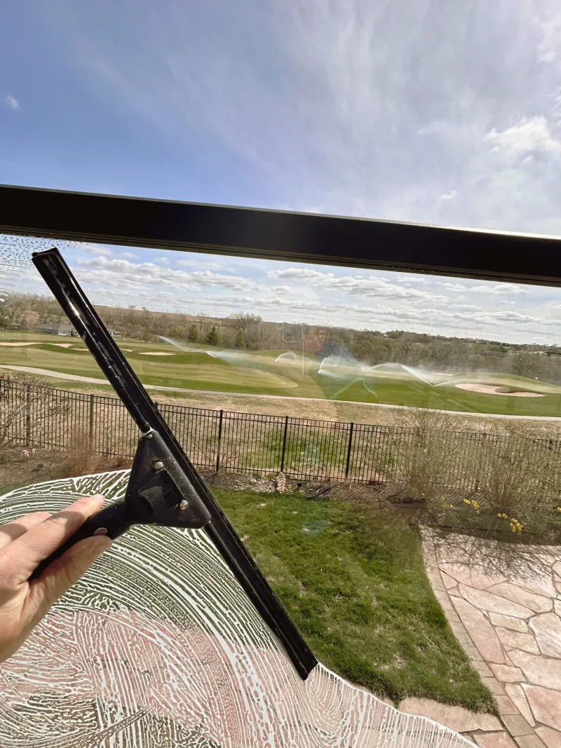 Squeegee pass on a window overlooking a green lawn