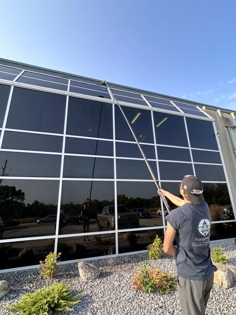 Technician cleaning a commercial glass storefront with a water-fed pole