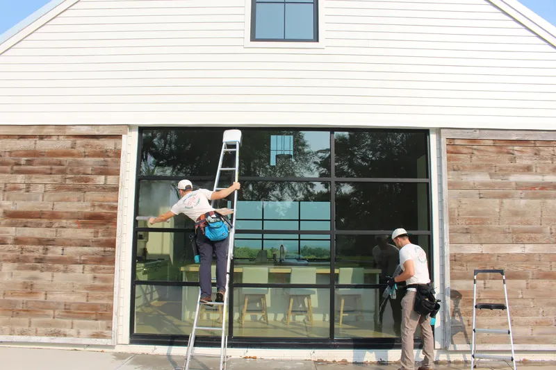 Two technicians on ladders cleaning a commercial building