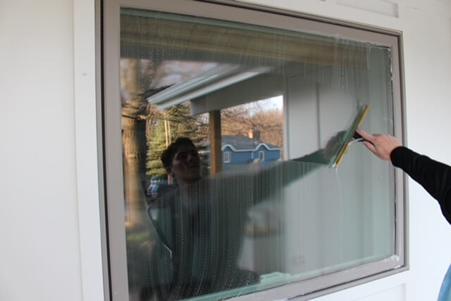 best window cleaning in omaha, Professional Window Cleaner using squeegee to reveal a perfectly clear residential window